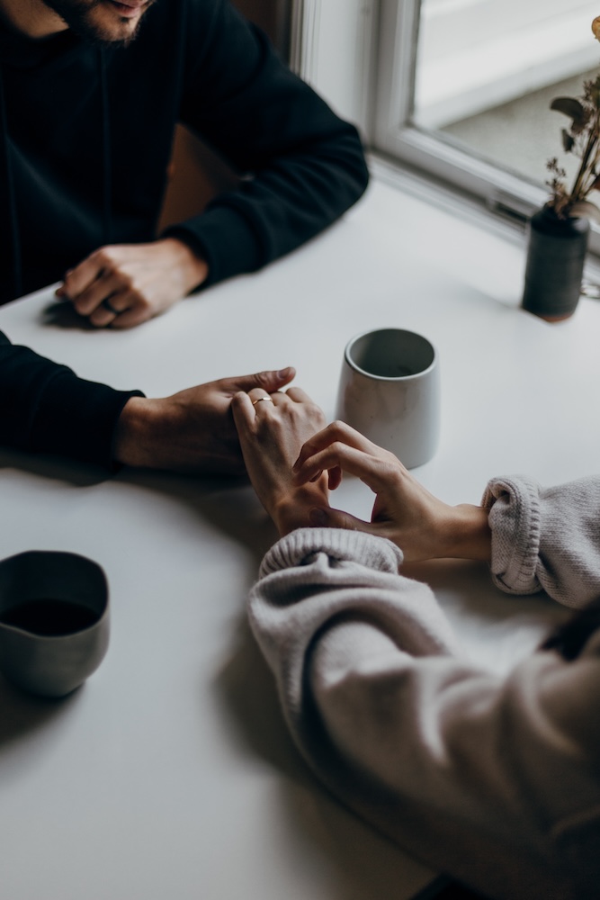 Couple holding hands across a table priscilla du preez xm4wunvbckk unsplash