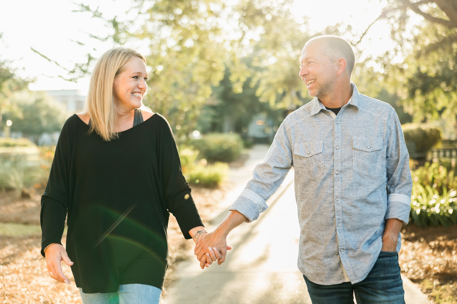 Couple holding hands, smiling at one another, and walking together